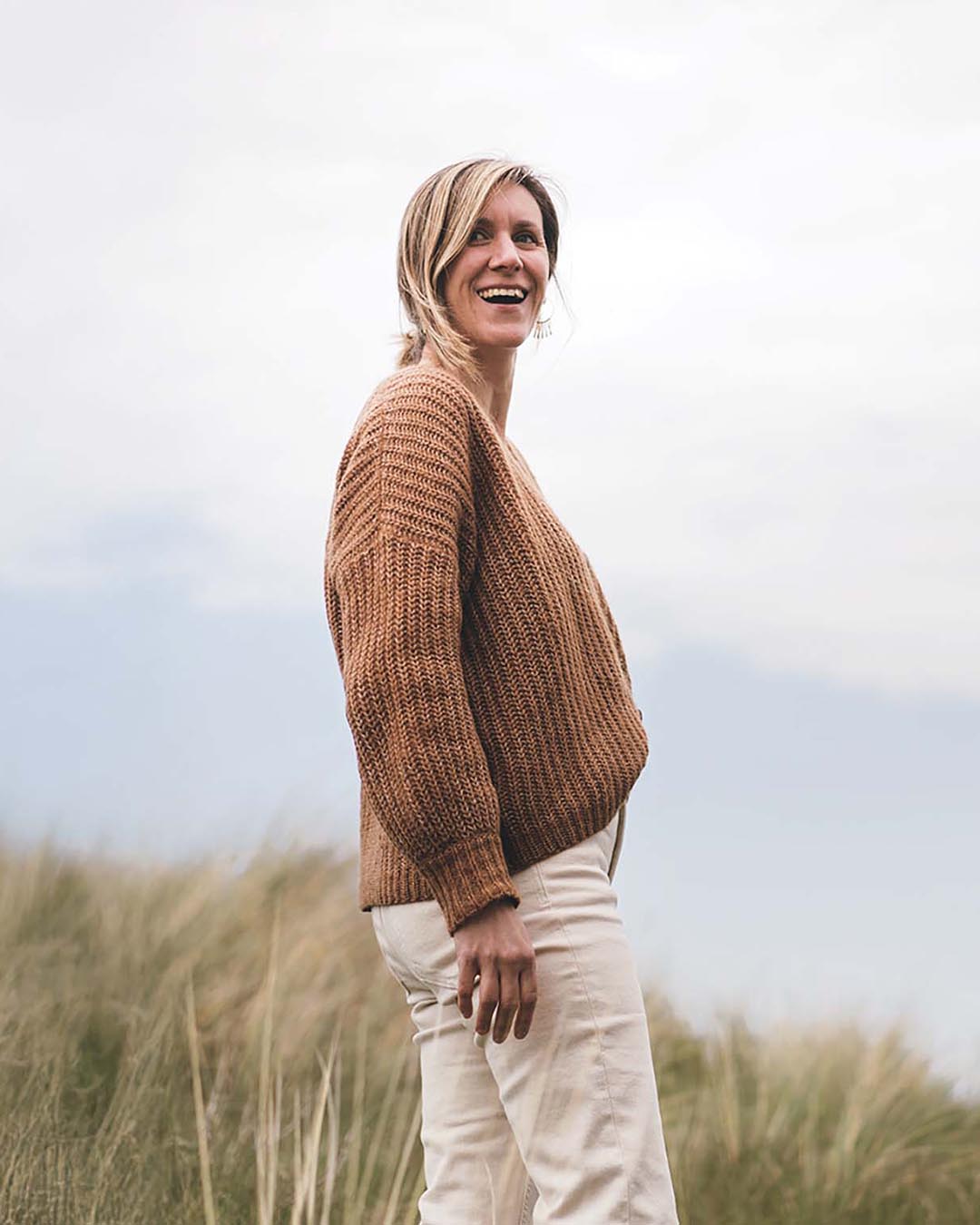 Portrait de Justine Guillo, femme debout dans les dunes en bord de mer