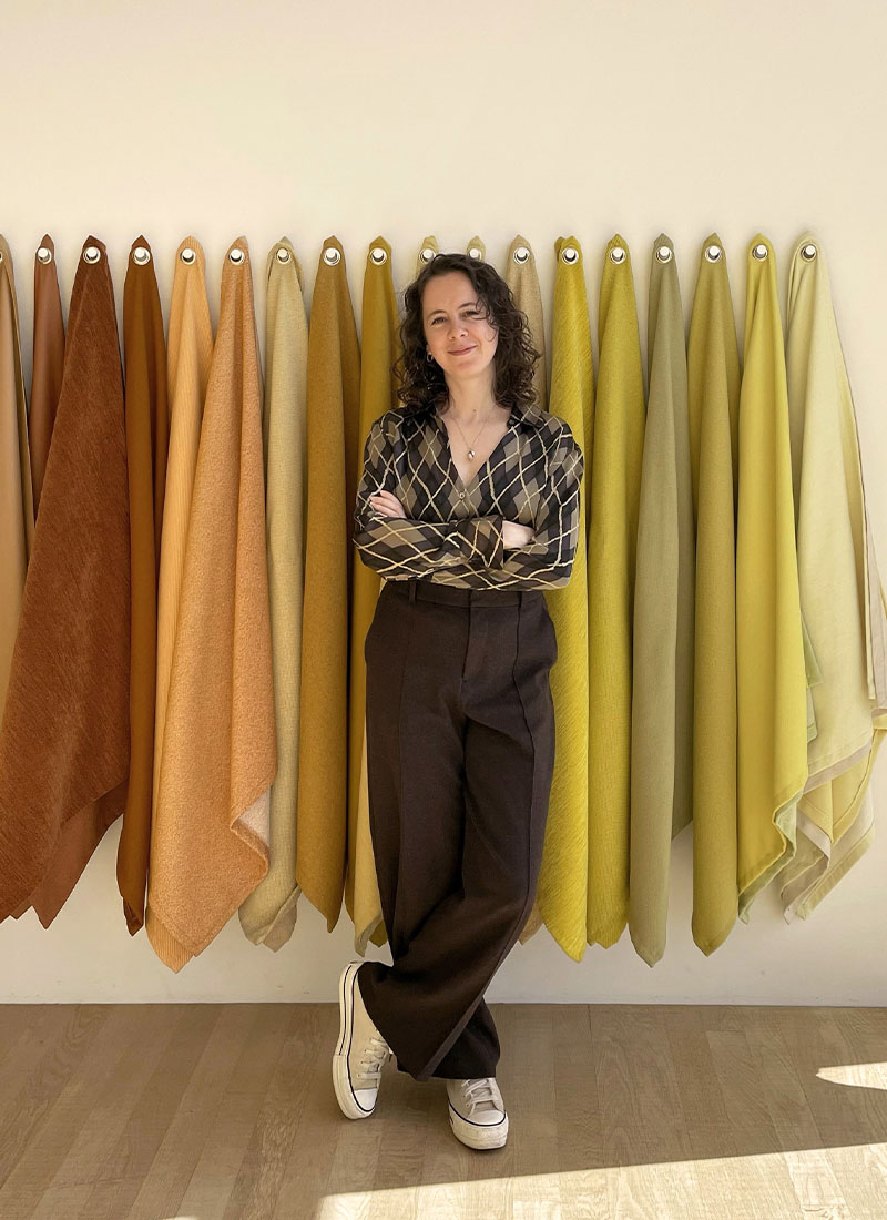 portrait claire debout devant des échantillons de tissus